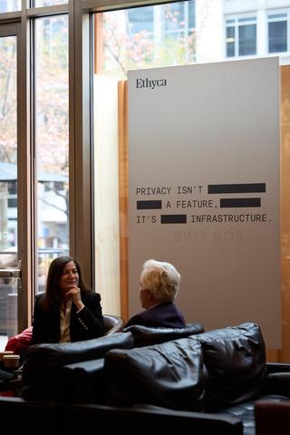 Ethyca poster on the window with two people talking.