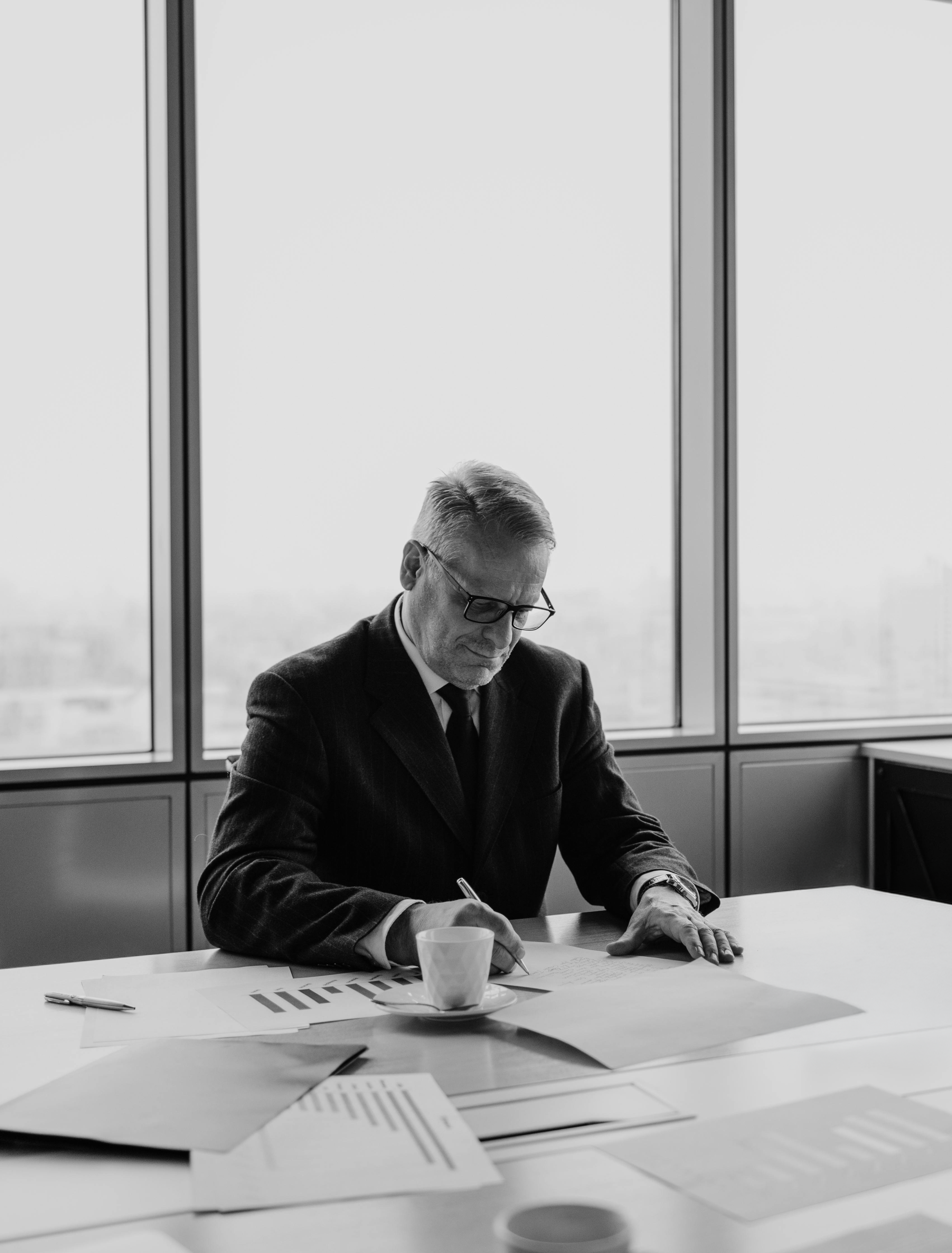 grayscale-photo-of-man-sitting-at-the-table