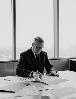 grayscale-photo-of-man-sitting-at-the-table