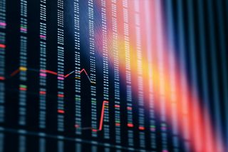 Close-up of a stock market screen with numerical data, colorful highlights, and a red line graph, set against a dark background