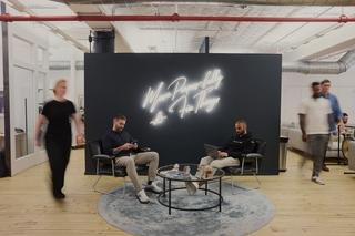 Office environment with people walking in front of a blue wall.