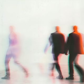 Abstract image of blurred figures in motion with red, green, and blue overlays, creating a dreamlike and mysterious atmosphere