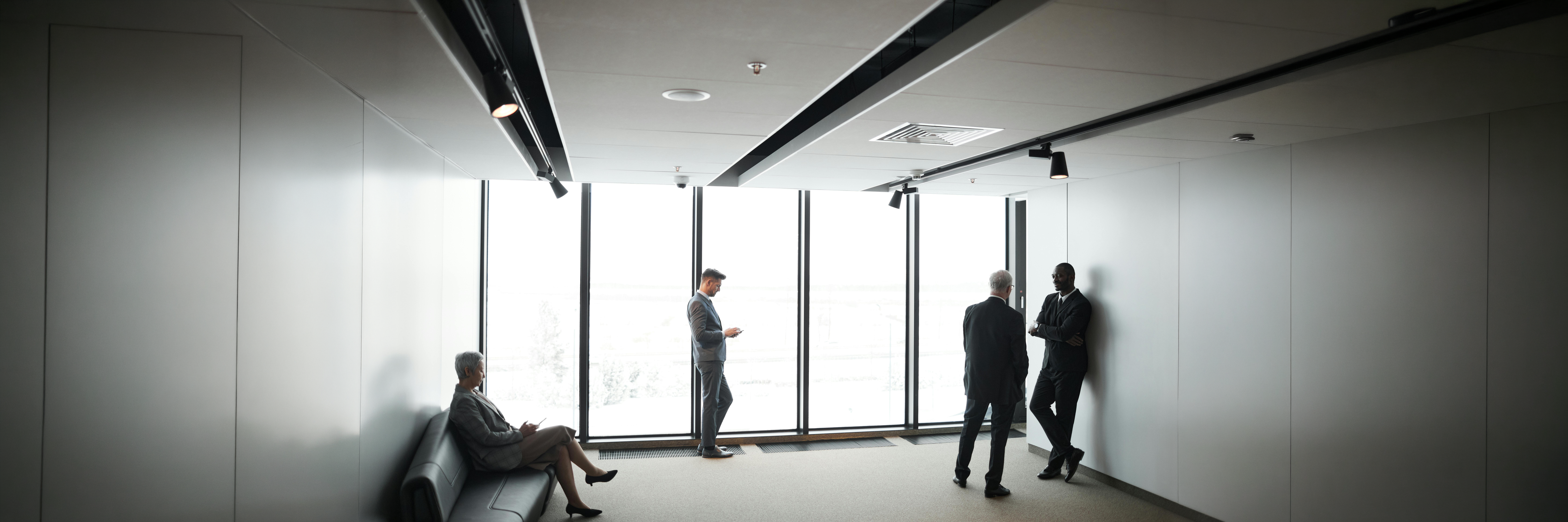a-man-in-gray-suit-standing-near-glass-window-in-the-office