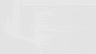 A person sitting in front of a computer screen with code, in black and white.