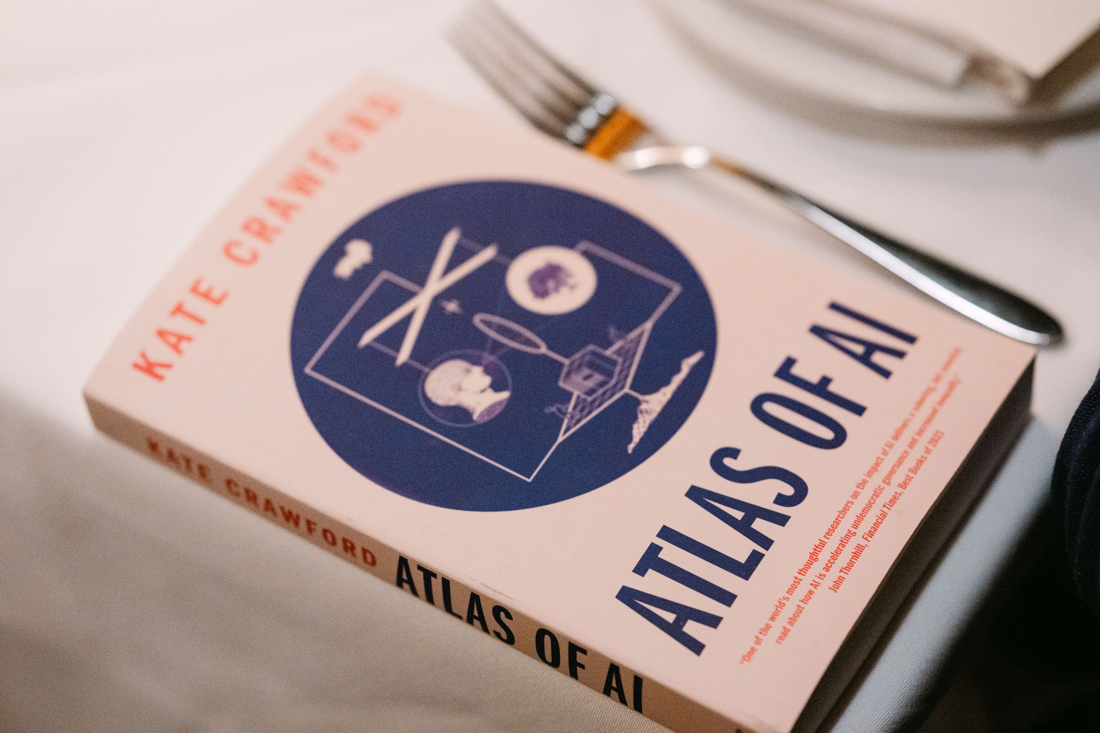 A book on a white tablecloth dining table.