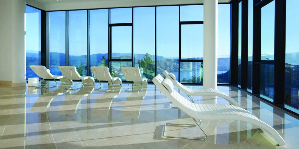 White sun loungers in a room with panoramic glazing overlooking the hills and lake