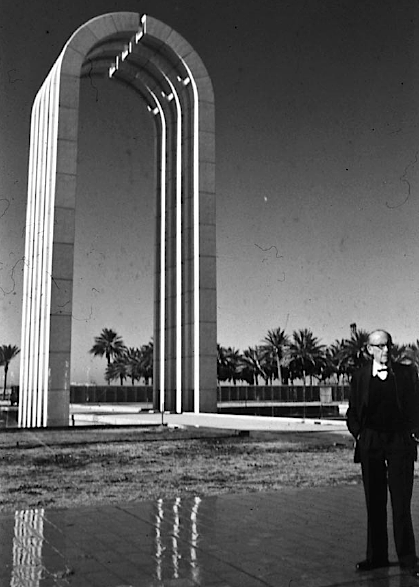 The ceremonial arch of the university complex in Baghdad, with a man in a suit standing nearby