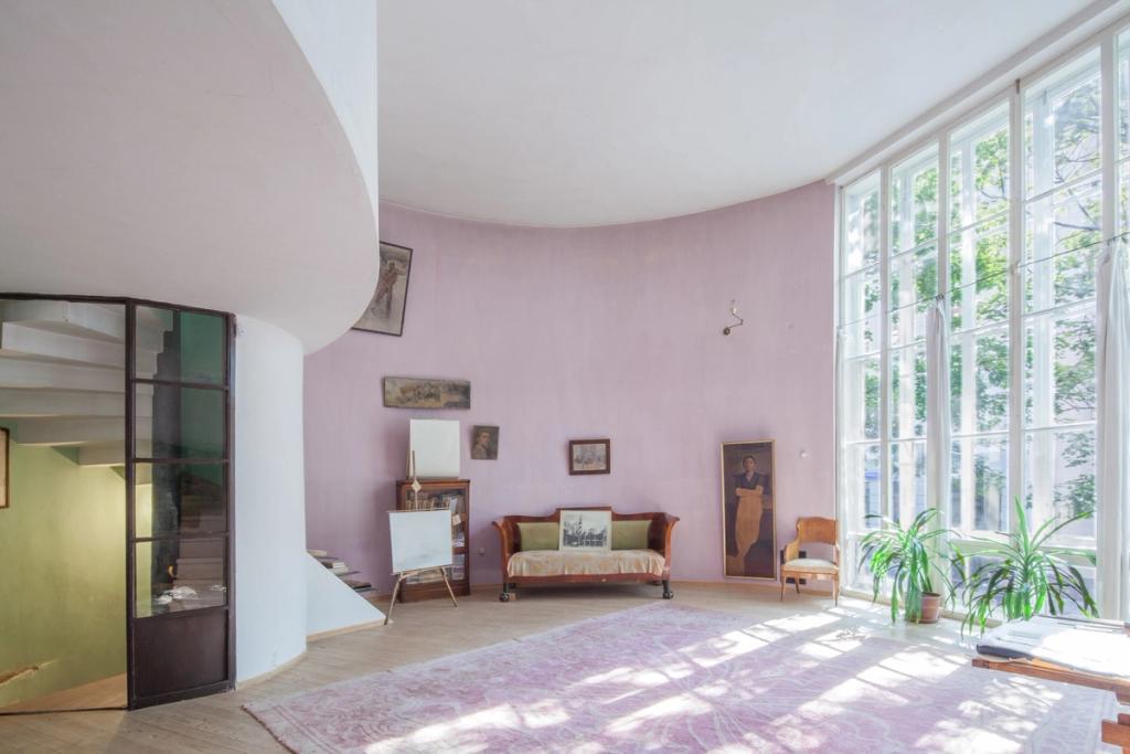 The living room of the Melnikov House with lilac walls and a tall floor-to-ceiling window
