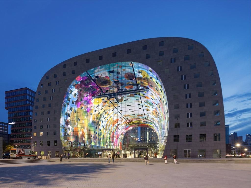 The covered Markthal market in Rotterdam, arch-shaped with a vivid painted vault, photographed at dusk