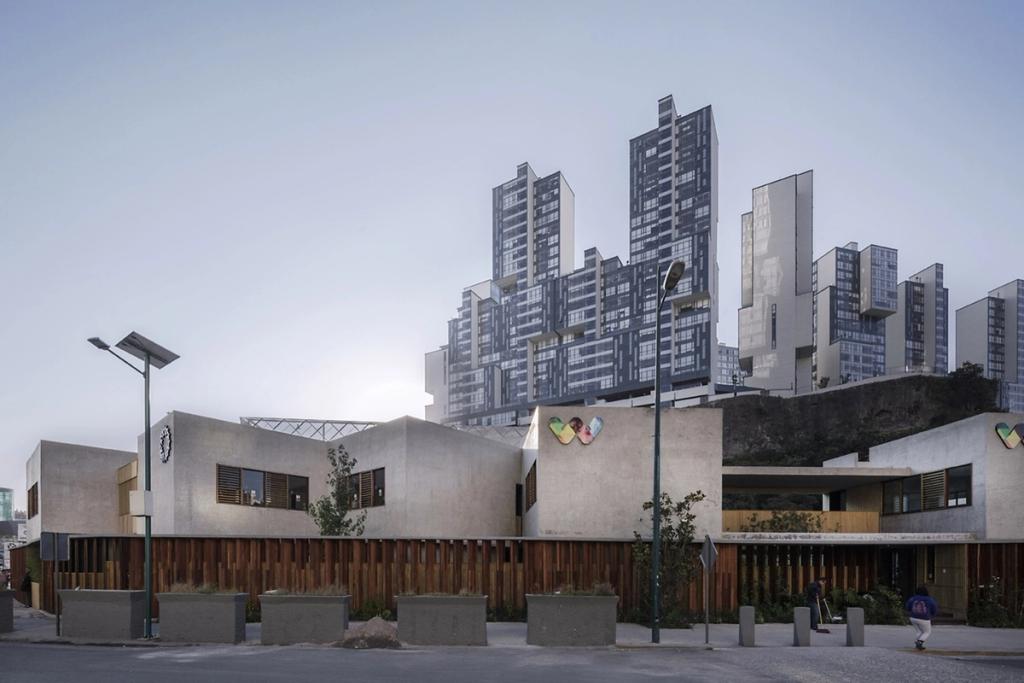 Walden Dos School: a concrete block with timber screening set against a backdrop of high-rise towers