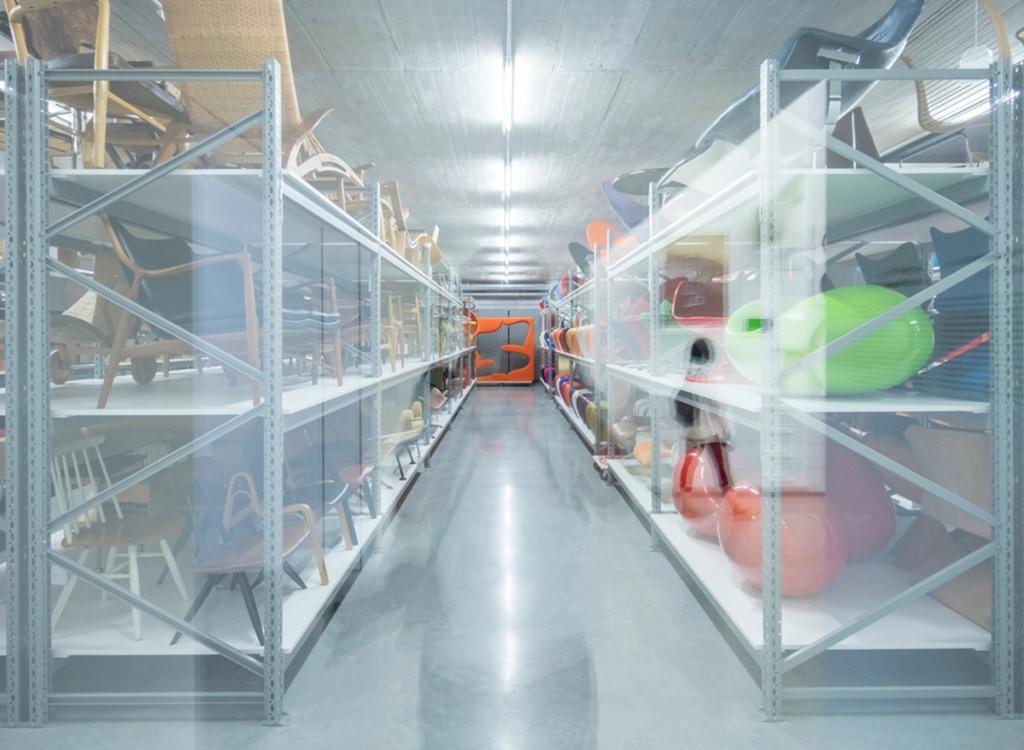 Проход хранилища Schaudepot со стеклянными стеллажами, полными стульев и предметов мебели