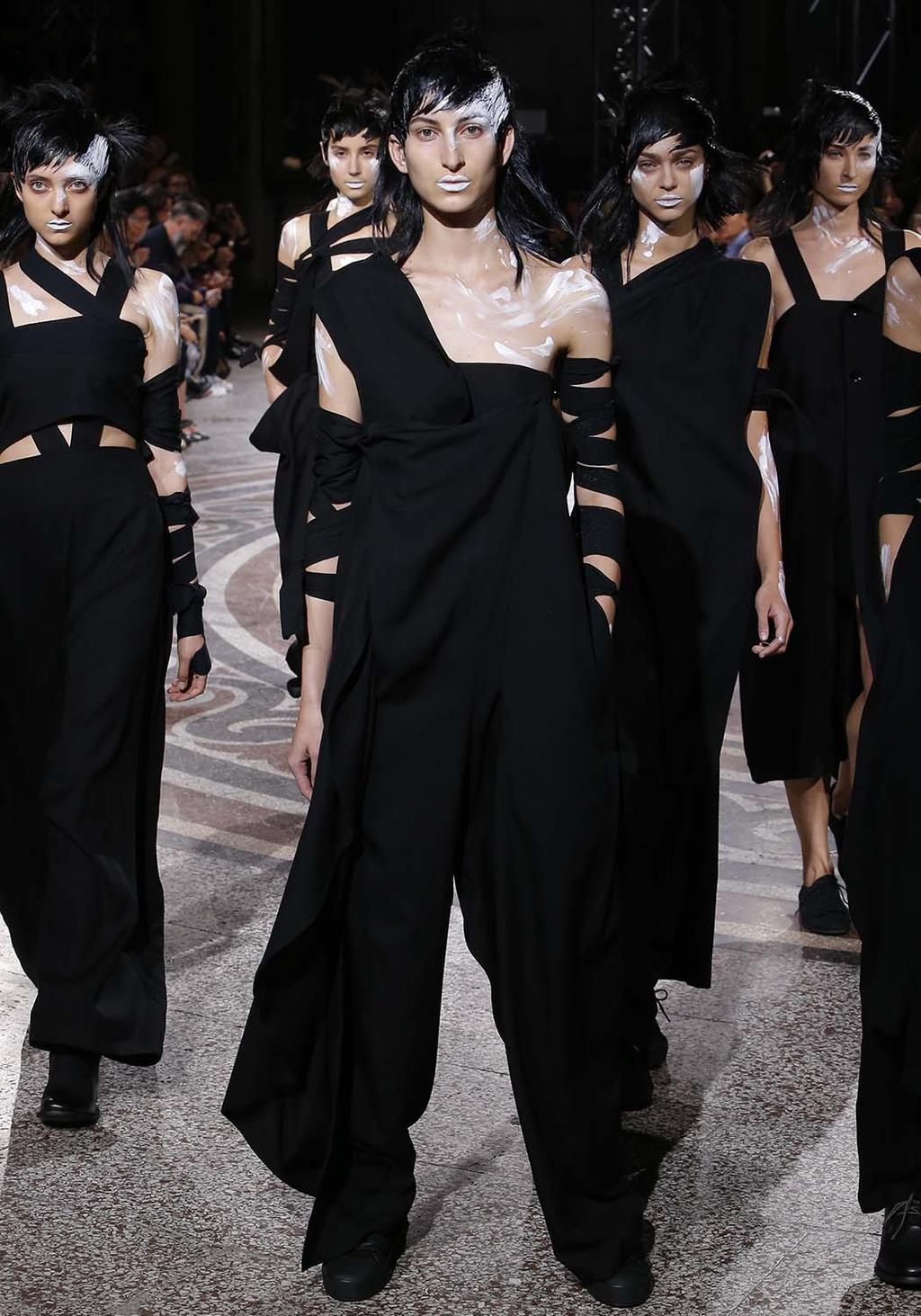 Models in all-black looks with ribbon-wrapped arms and white face paint
