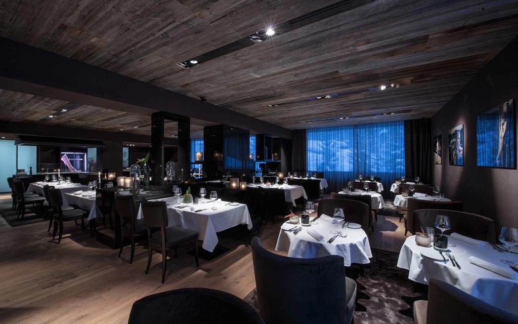 The hotel restaurant with a dark wooden ceiling and laid white-clothed tables