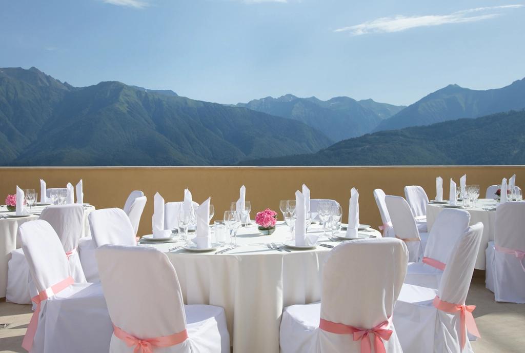 Banquet tables with white covers on a terrace overlooking the mountains of the Caucasus