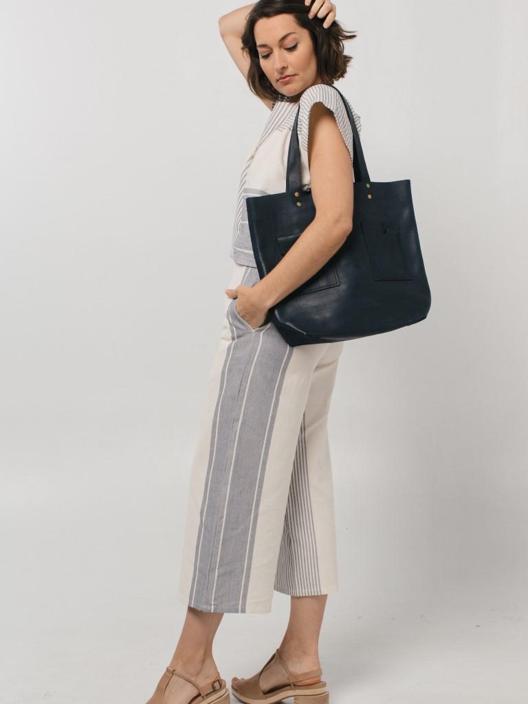 A model in striped culottes with a dark navy leather tote bag on her shoulder by Tribe Alive