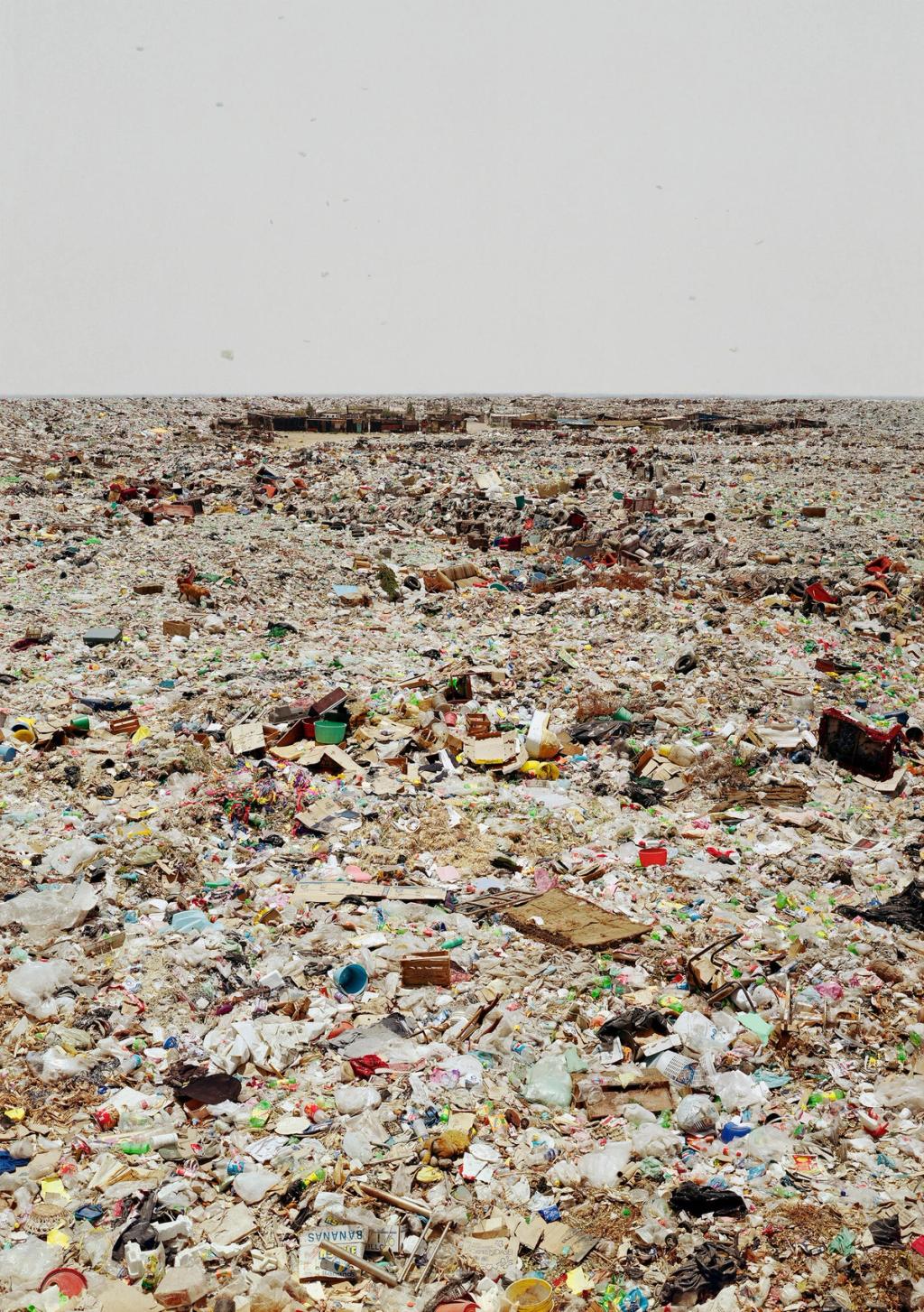 A vast field of rubbish and plastic waste stretching to the horizon beneath a pale sky