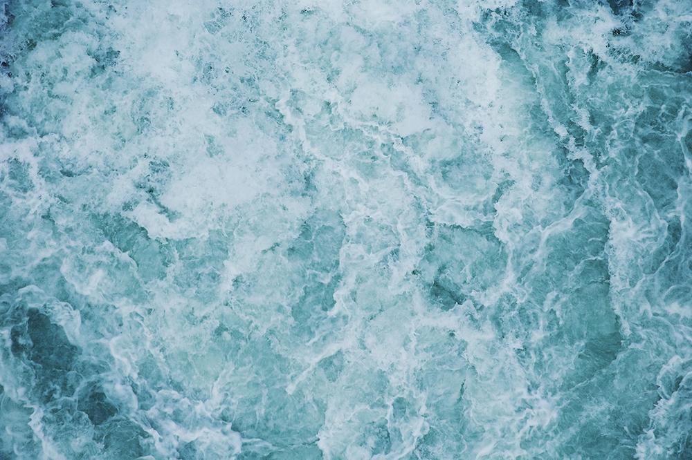 Бирюзовая морская вода с пеной волн, снятая сверху крупным планом
