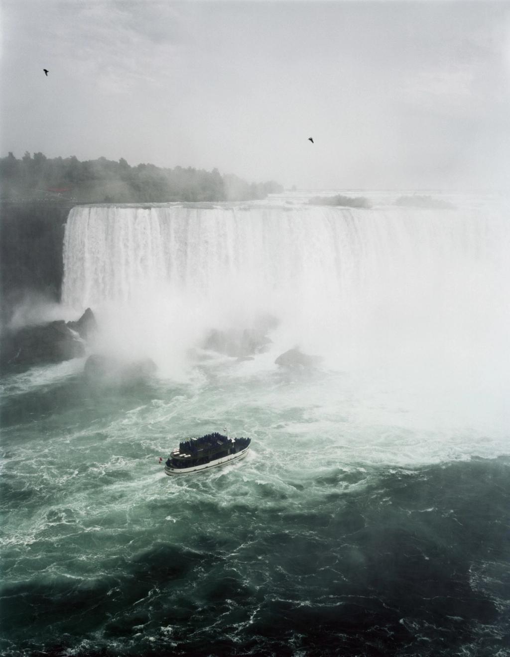 A pleasure boat in the churning water at the foot of Niagara Falls, shrouded in spray