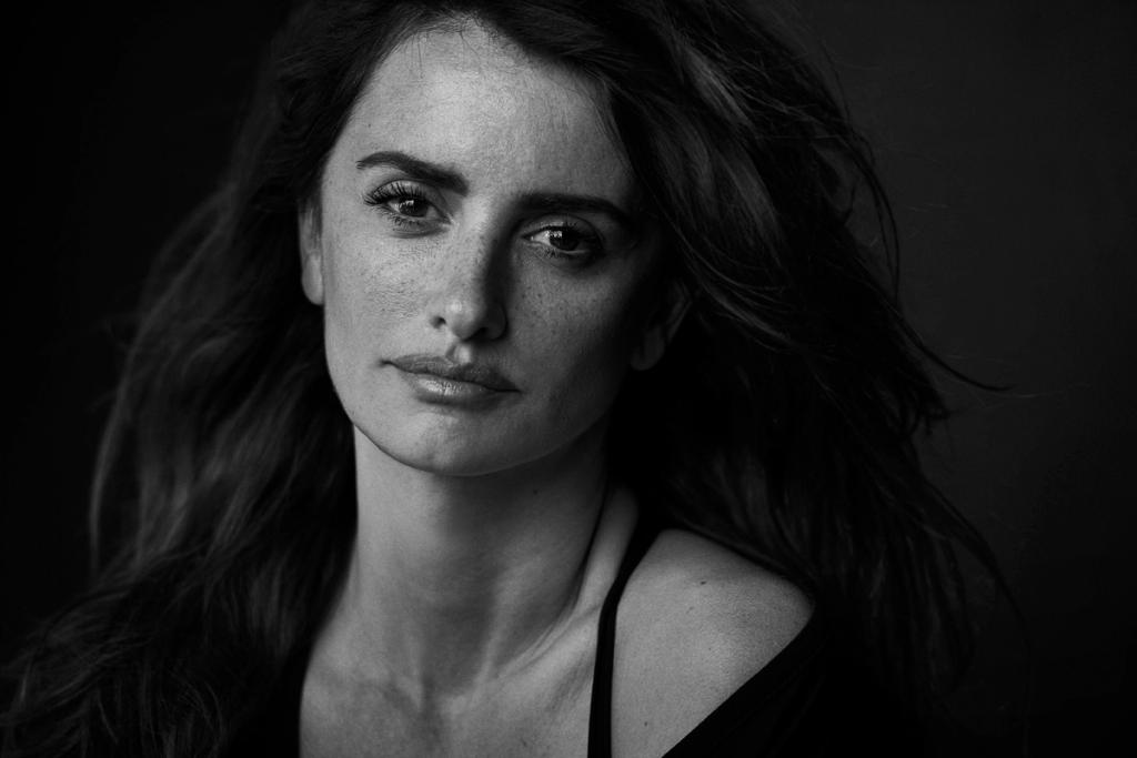 Black-and-white close-up portrait of a dark-haired woman against a dark background