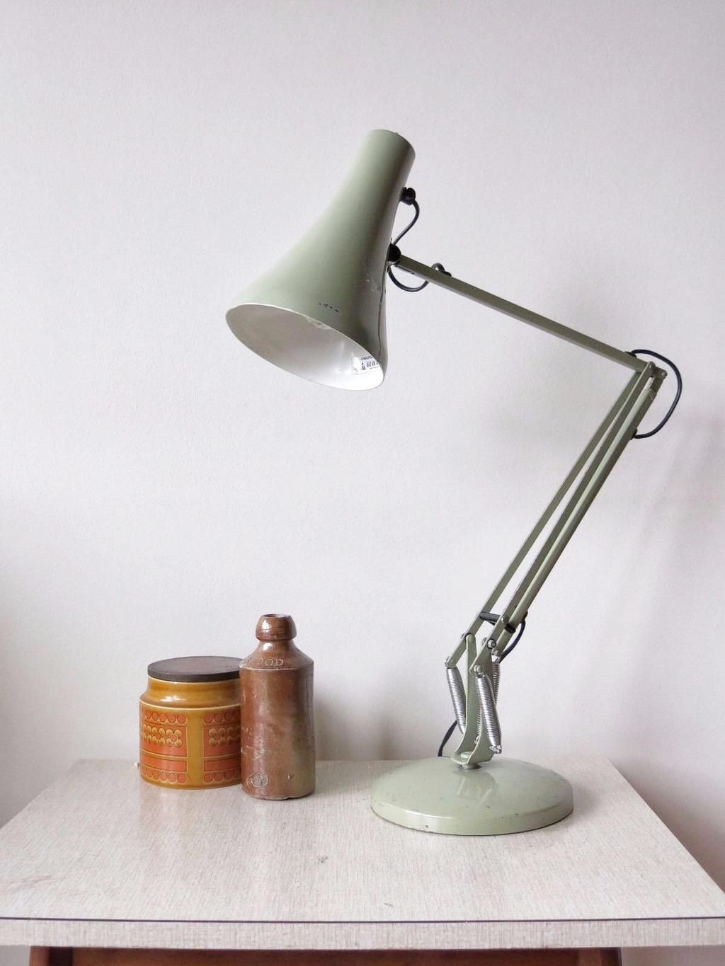 Светло-зелёная лампа Anglepoise на круглом основании рядом с керамическими банками
