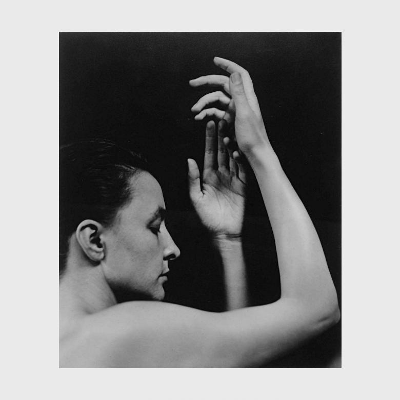 A Stieglitz black-and-white photograph: O'Keeffe in profile with her arms raised