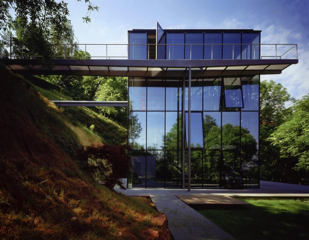 The exterior facade of house R-128, fully glazed and set among trees