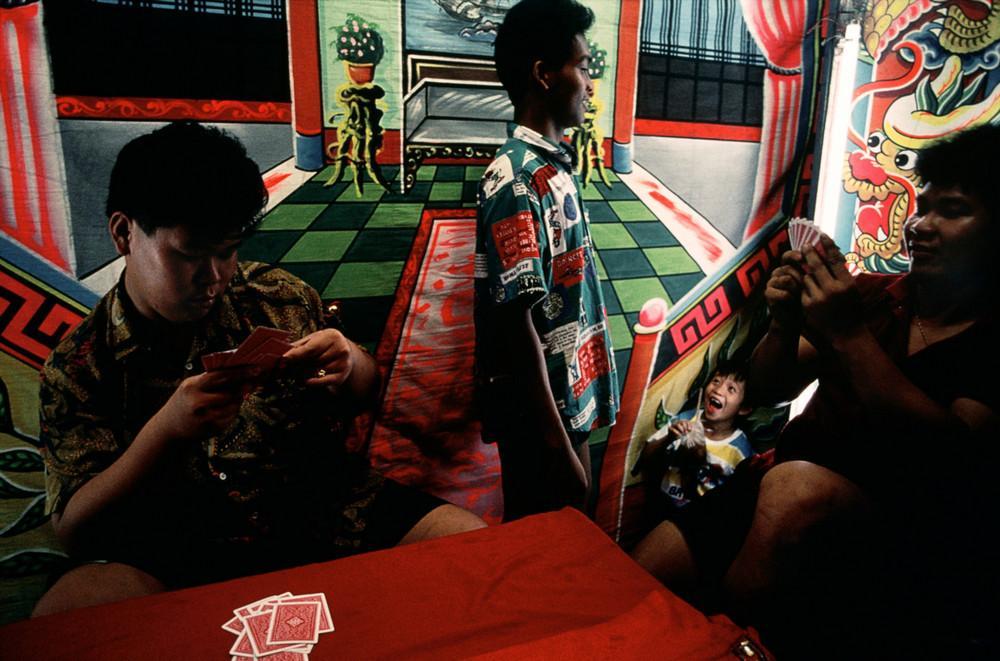 Young men playing cards in a room with painted dragons on the walls
