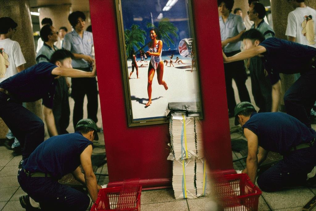 Workers in blue uniforms installing a billboard in a Tokyo underpass