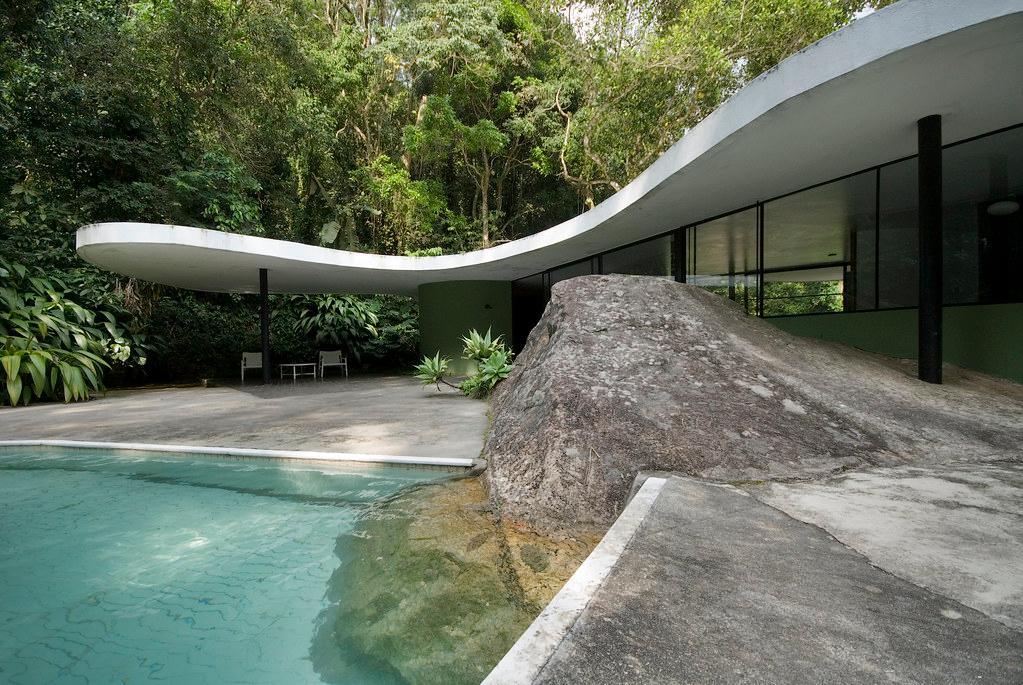 The curved white roof of Casa Canoas, the pool and a natural boulder beside the house