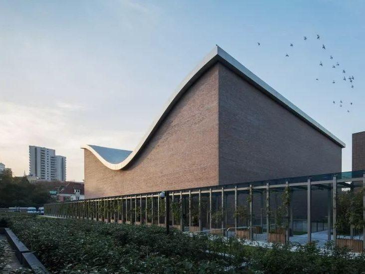 The Shanghai Symphony Hall: a brick volume with an undulating roof and a glazed gallery