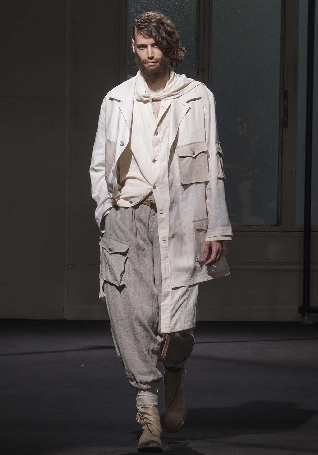 A man in a white linen coat and wide light-coloured trousers on the runway