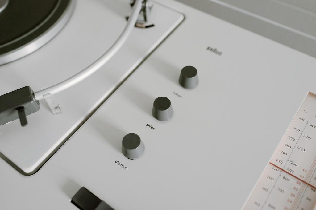Close-up of three grey höhen, tiefen and volumen knobs alongside the turntable's tonearm