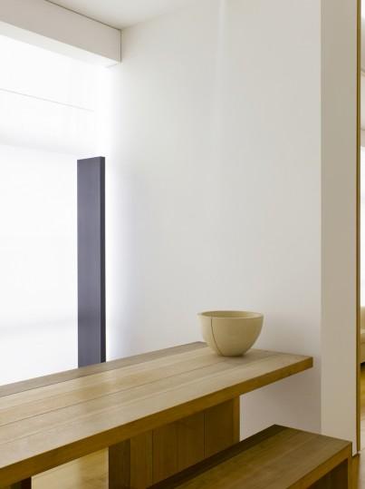 A wooden bench against a white wall with a pale ceramic bowl — a minimalist interior