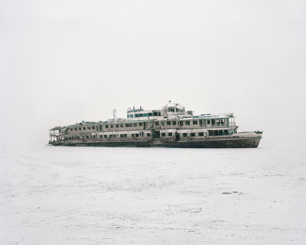 An abandoned multi-deck river steamboat, frozen into a snow-covered riverbed