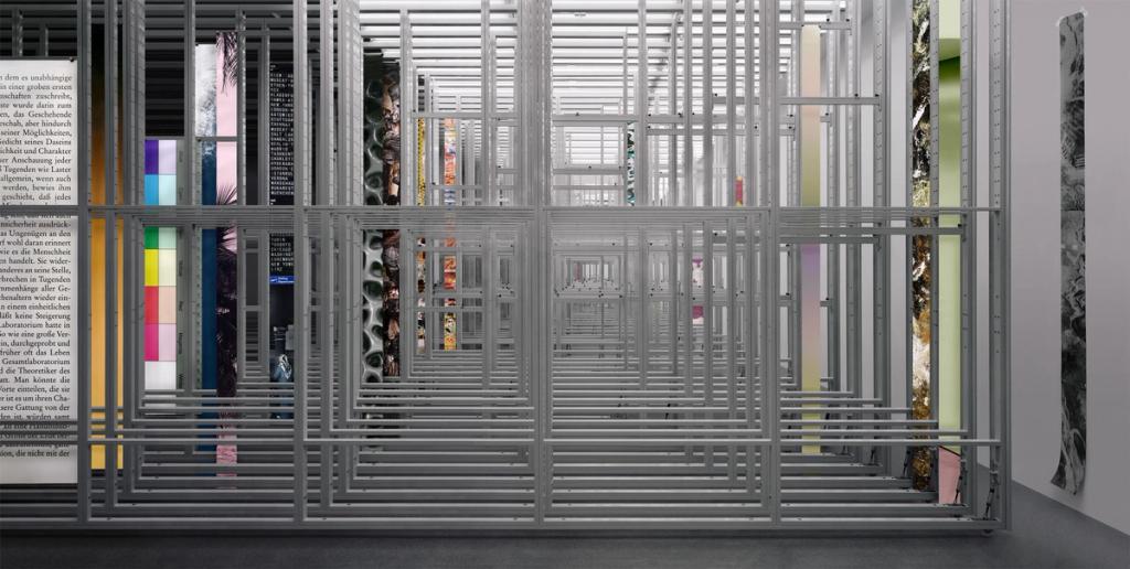 A complex lattice installation with coloured inserts and text across the gallery walls