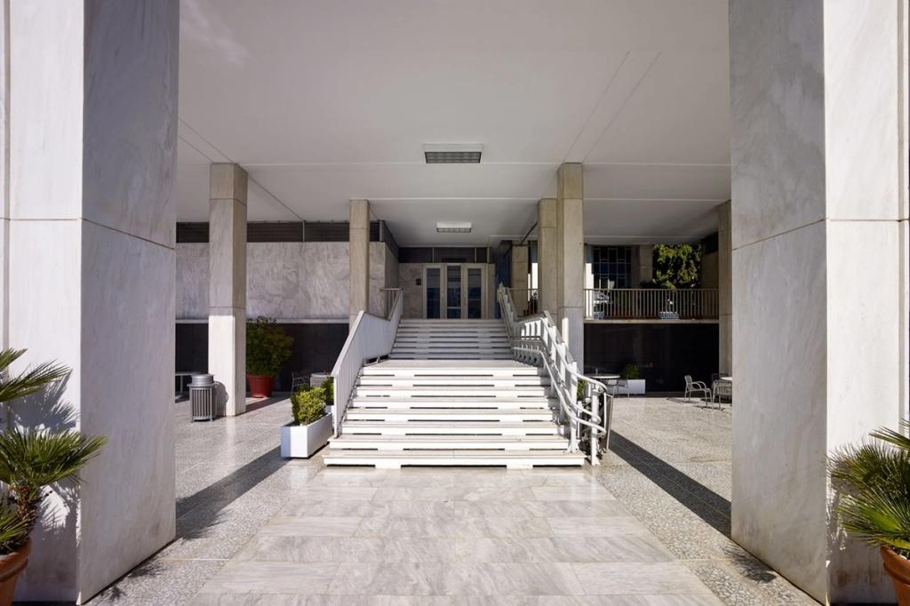 The marble entrance hall of the US Embassy in Athens, with columns and a broad ceremonial staircase