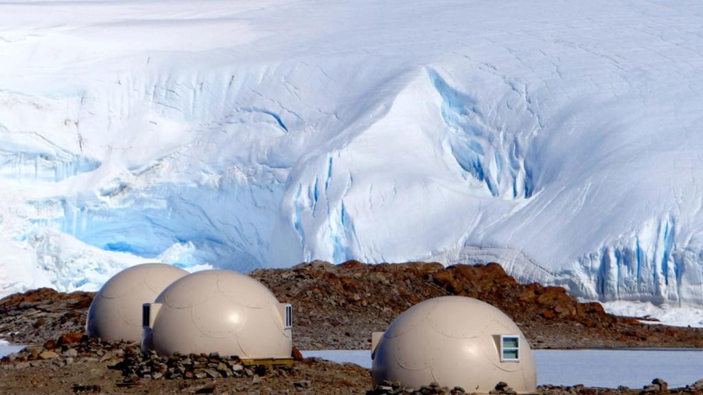 The dome cabins of the Whichaway camp against an Antarctic glacier