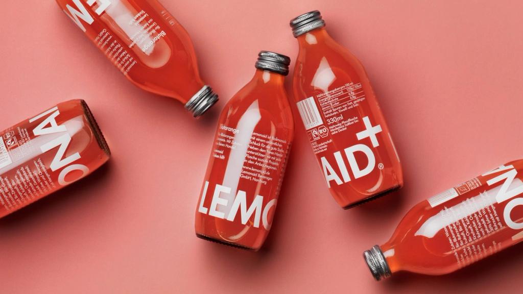 Красные бутылки Lemonaid лежат на розовом фоне