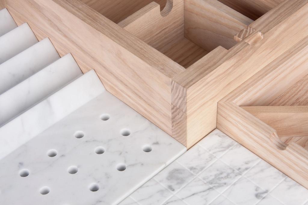 A close-up of a wooden organiser with marble elements and a perforated marble plate