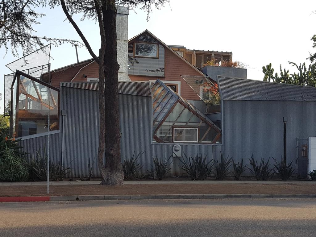 Frank Gehry's house clad in corrugated metal, with an angled glass cube window