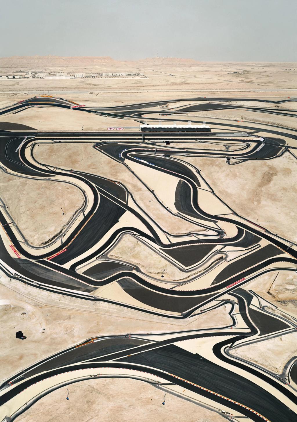 A winding motor-racing circuit seen from above, cutting through a sandy desert