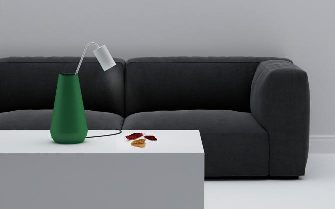 A table lamp in the form of a green vase on a white table beside a dark grey sofa, designed by Maxim Maximov