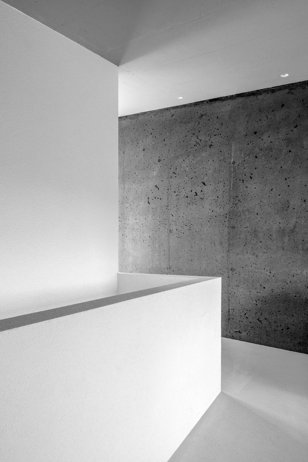 A minimalist interior with a white wall and a contrasting textured concrete surface