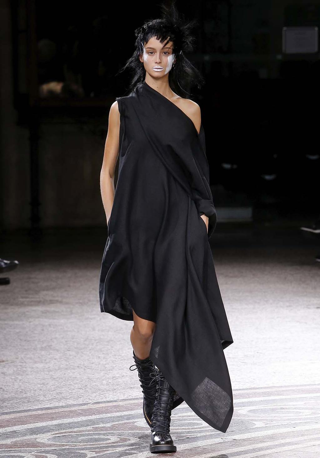 A black draped one-shoulder dress worn with lace-up ankle boots