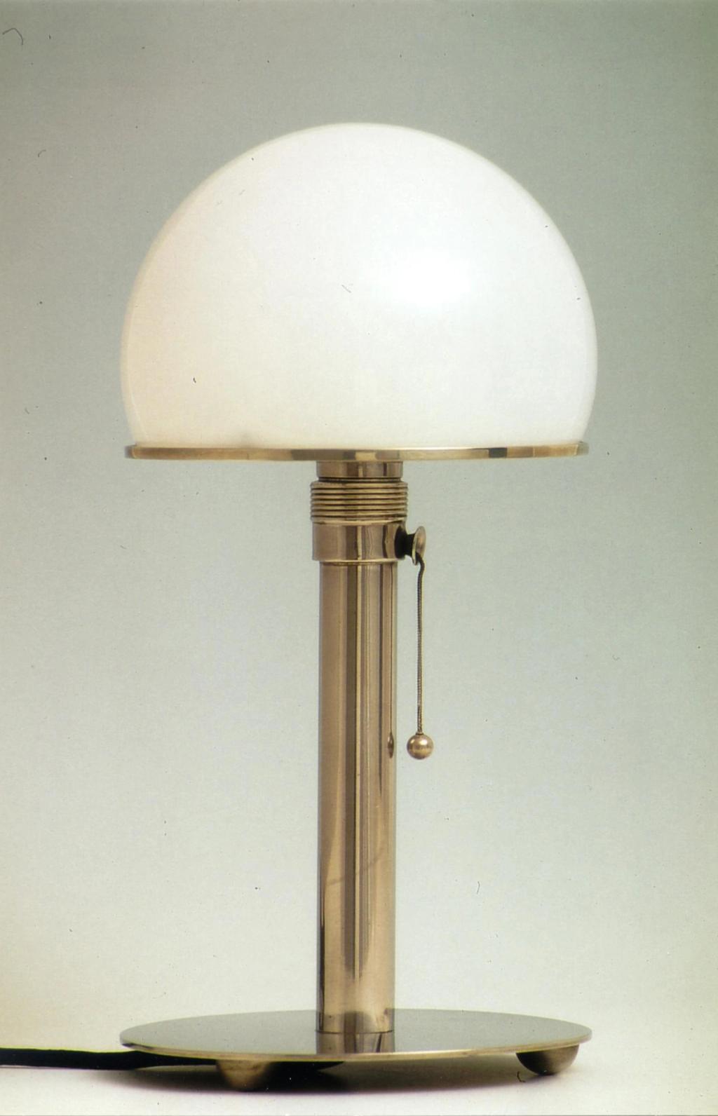 A Wagenfeld table lamp with a white glass hemispherical shade on a metal stem