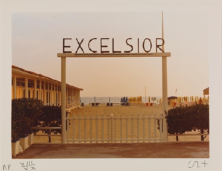 A photograph of beach gates bearing the inscription Excelsior, with the sea in the background