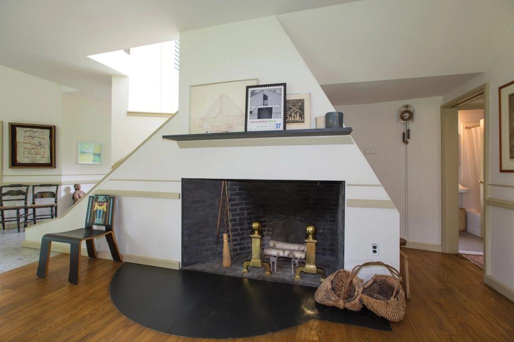 The living room of the Vanna Venturi House, with a large fireplace and a staircase behind it