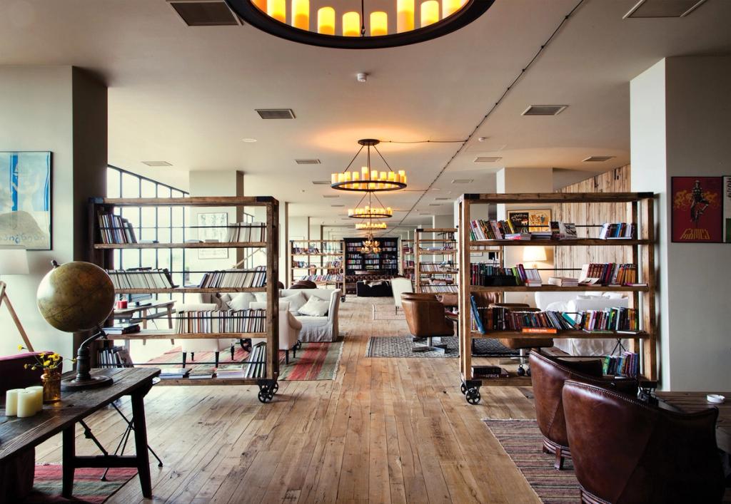 A spacious hotel lounge with wooden shelving, books and vintage chandeliers