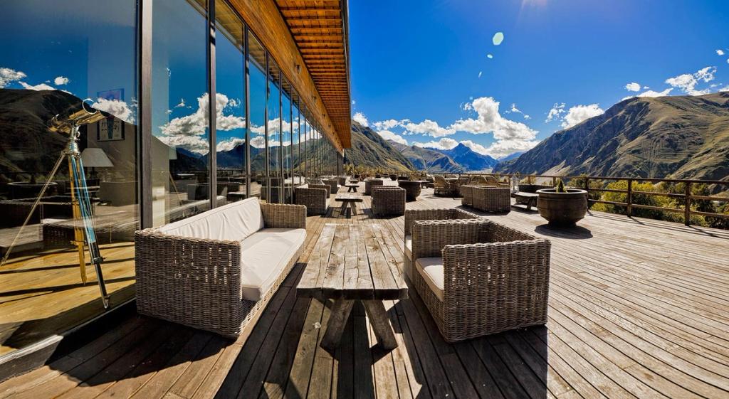 The wooden terrace of Rooms Kazbegi with wicker furniture and views of the Georgian mountains
