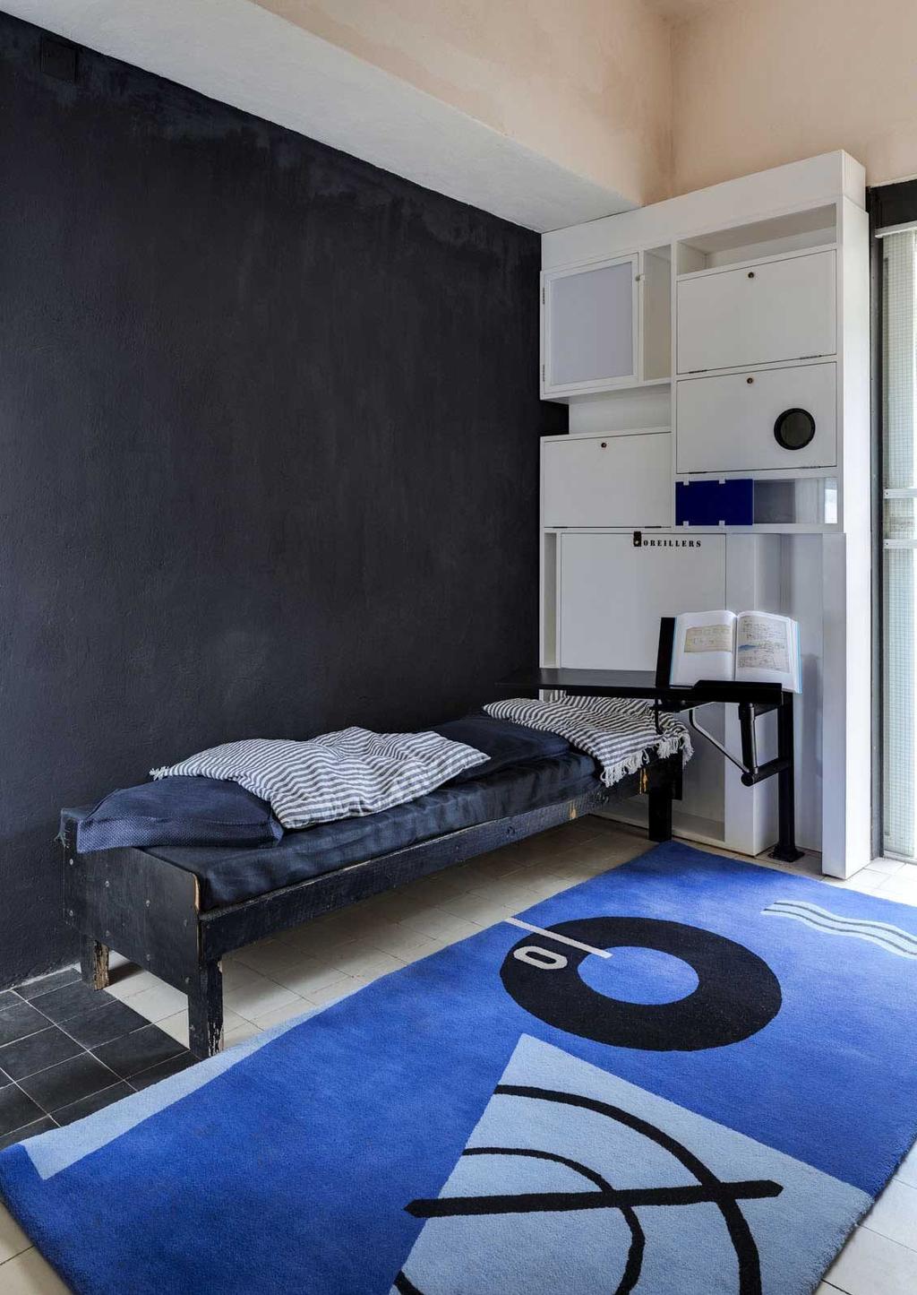 Bedroom of Villa E-1027 with a black wall, a narrow chaise longue and a blue rug with a geometric pattern